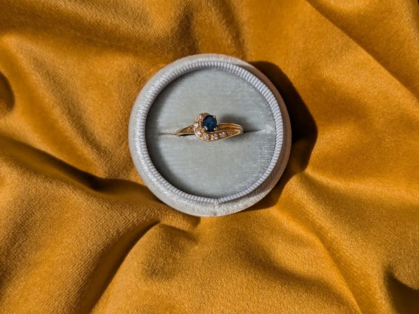 Blue sapphire ring in a ring box on mustard velvet